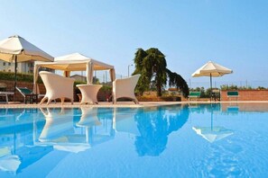 A swimming pool with lounge chairs and umbrellas.