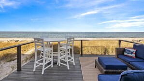 Una terrazza con tavolo e sedie vista spiaggia.