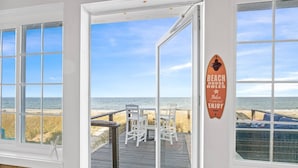 Una casa sulla spiaggia con vista sull'oceano, un patio in legno e un cartello con le regole della casa.