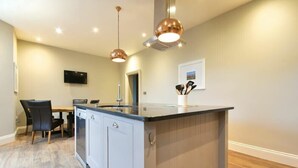 Une cuisine moderne dotée d’un îlot central, de luminaires suspendus et d’un coin repas avec des chaises et une table.