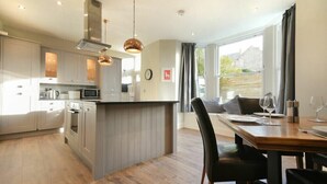 Une cuisine moderne dotée d’un îlot central, de planchers en bois et de luminaires suspendus.