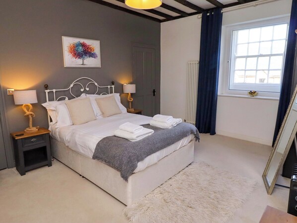 A bedroom with a bed, bedside lamps, a radiator, a window with curtains, and a painting on the wall. - Treetops, Alnwick (Alnwick)