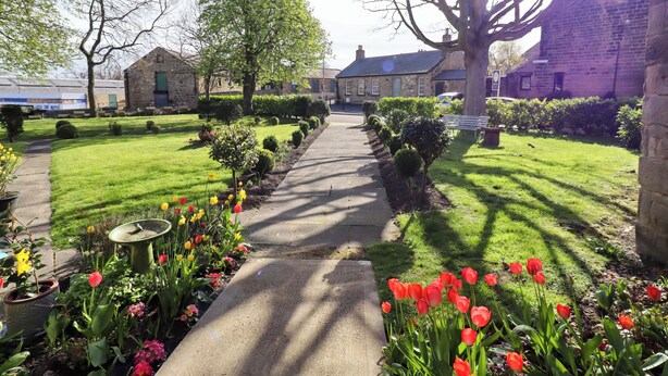 A pathway leading to a building with a stone facade, surrounded by well-maintained lawns and flowering plants. - Treetops, Alnwick (Alnwick)
