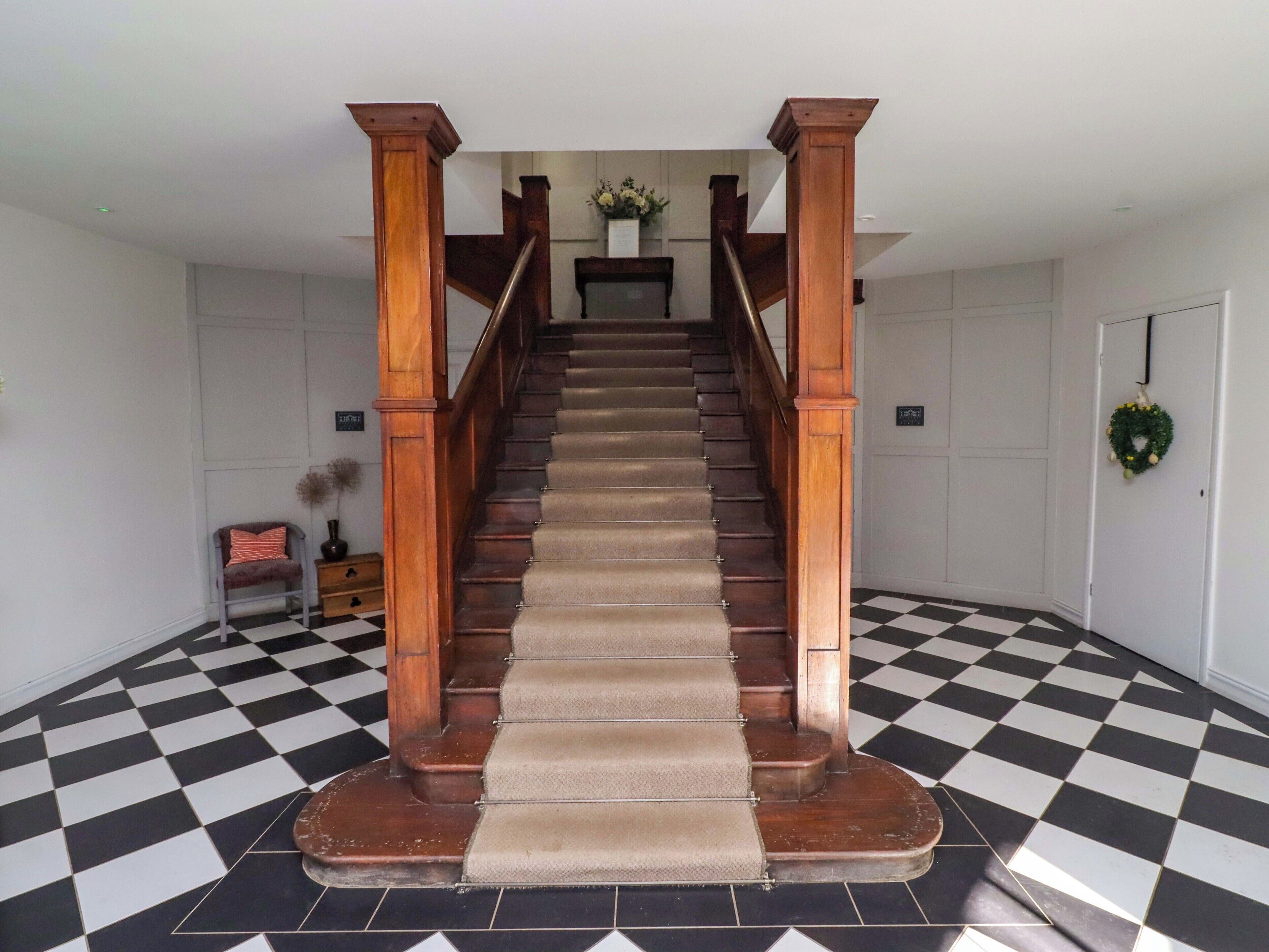 A staircase with wooden balusters and a checkered floor.