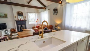 A modern kitchen with a marble countertop, gold faucet, and a large window. - Treetops, Alnwick (Alnwick)