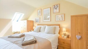 Ein Schlafzimmer mit einem Bett, einem Schminktisch, einem Kleiderschrank und gerahmten Bildern an der Wand.