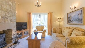 Ein gemütliches Wohnzimmer mit Kamin, bequemen Sitzgelegenheiten, einem Fernseher und einer Chandelier.