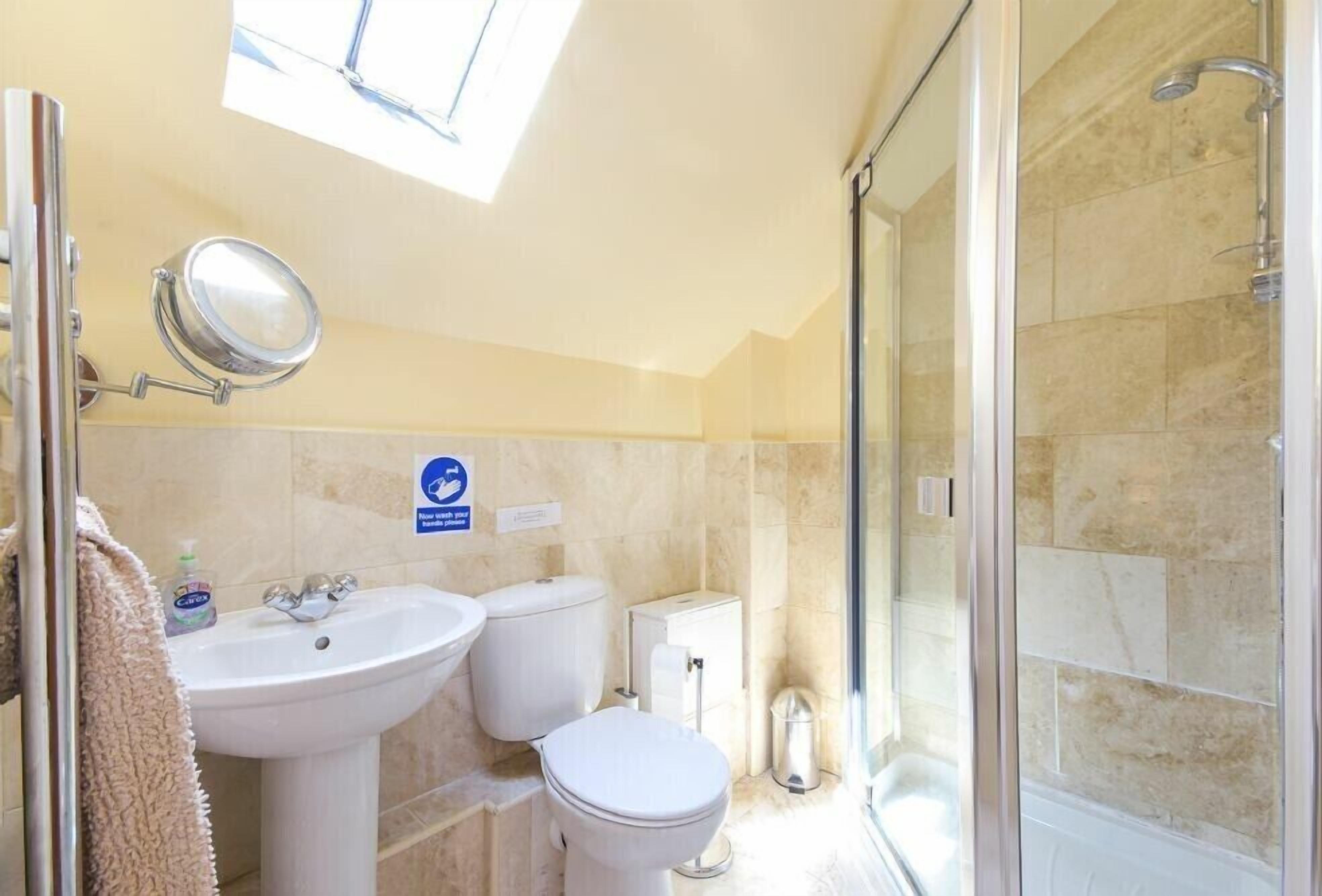Un baño moderno con cabina de ducha de vidrio, lavamanos e inodoro.