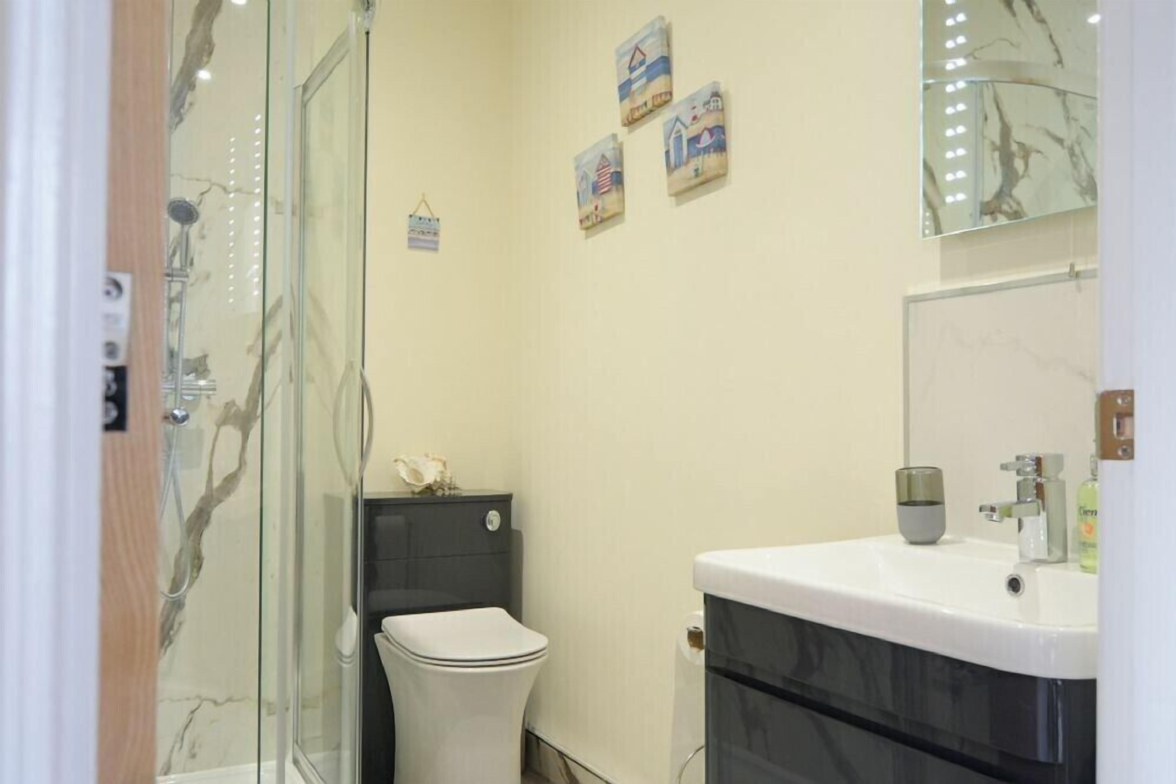 A bathroom with a glass-enclosed shower, a white toilet, a black sink, and a mirror above the sink.