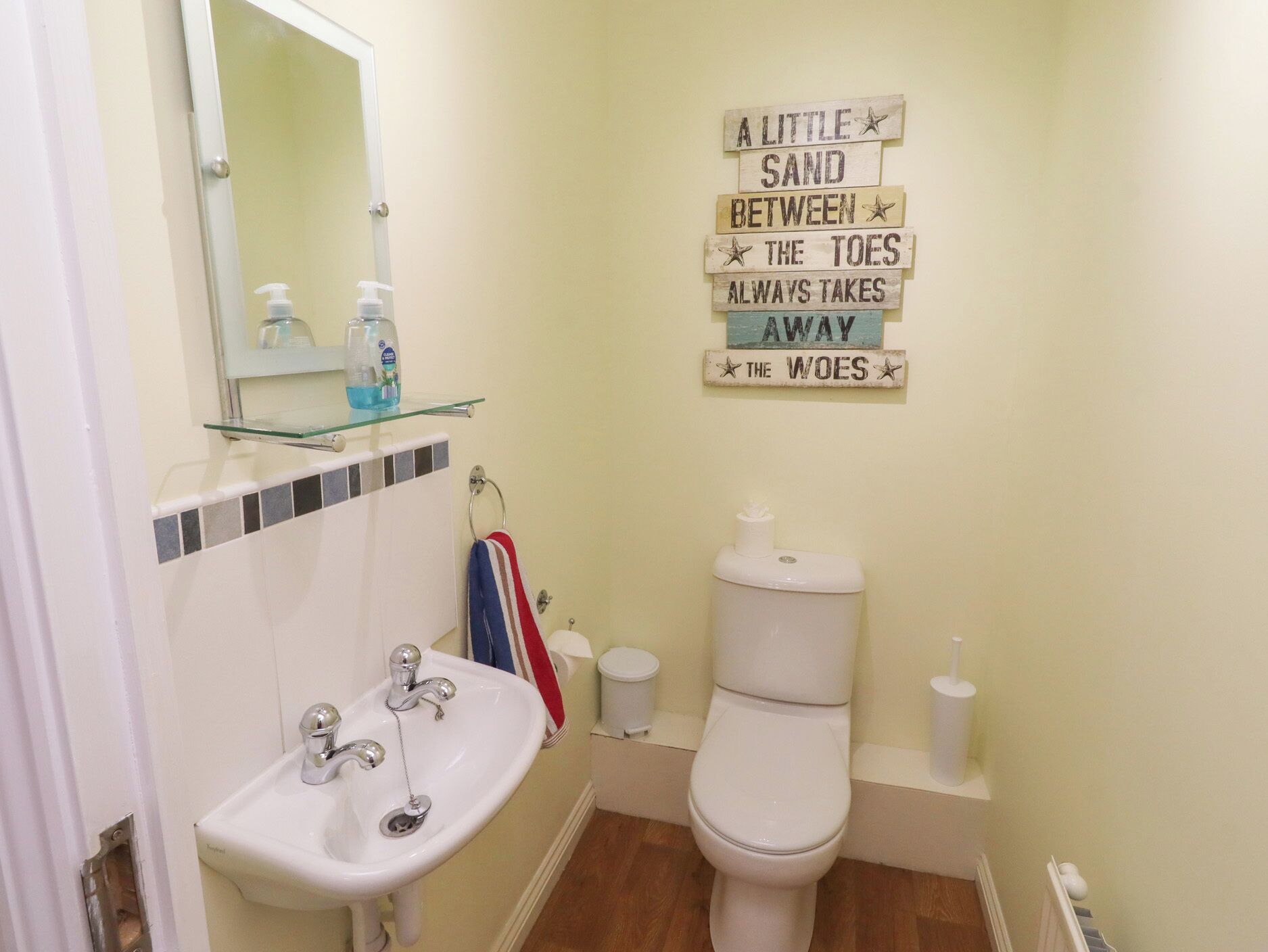 Ein Badezimmer mit Waschbecken, Toilette und einem an der Wand befestigten Schild.