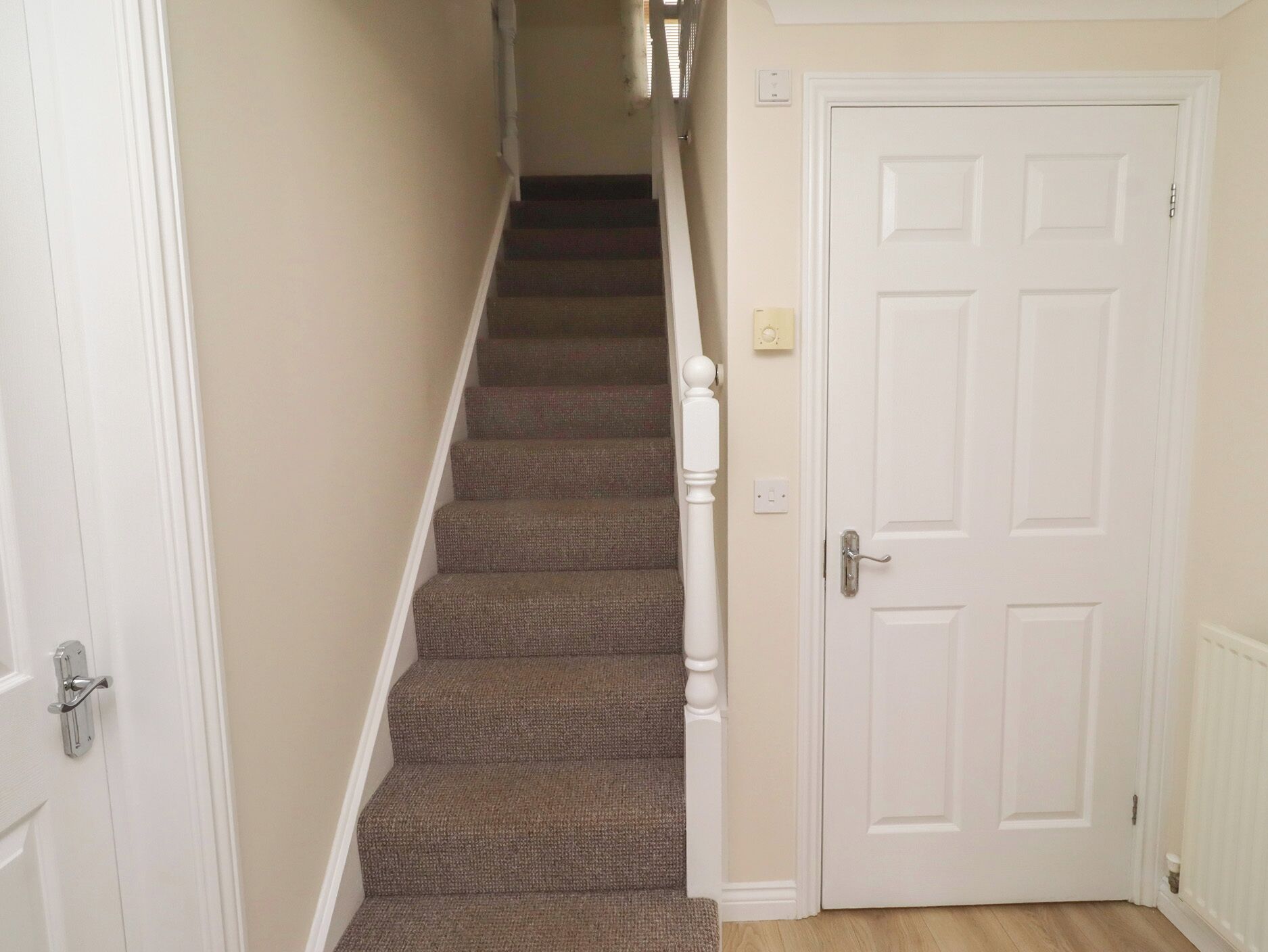 A staircase leading to a door with a white frame and a light switch on the wall.