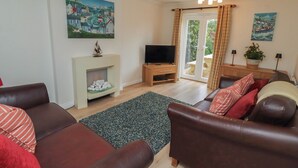 Ein Wohnzimmer mit Kamin, Fernseher und zwei Ledersofas.