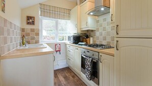 A compact kitchen with white cabinets, a gas stove, a microwave, and a sink.