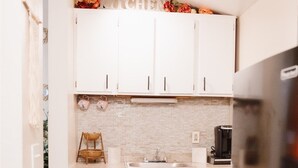 A compact kitchen with white cabinets, a black refrigerator, and a tiled backsplash. - Beautiful One Bedroom Apartment in The Neighbor of the Art (Rochester)
