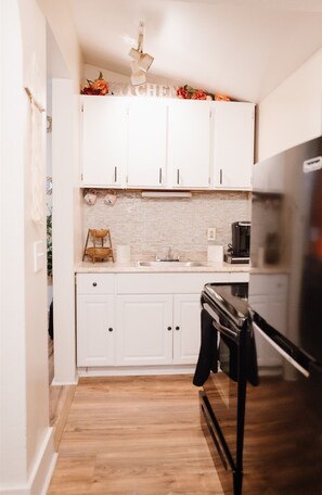 A compact kitchen with white cabinets, a black refrigerator, and a tiled backsplash. - Beautiful One Bedroom Apartment in The Neighbor of the Art (Rochester)