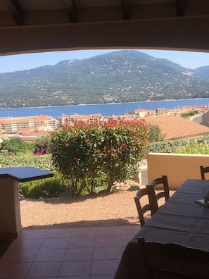 Une terrasse extérieure offrant une vue sur une ville côtière et les montagnes.