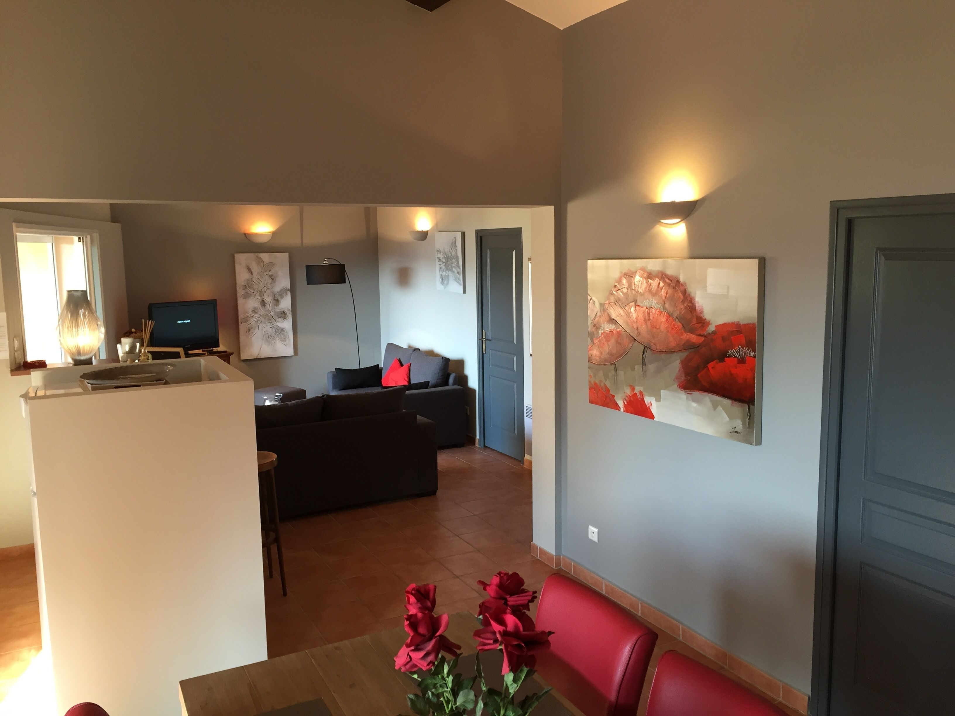 A modern living room with a sofa, a dining table with chairs, and a kitchen area with a TV.