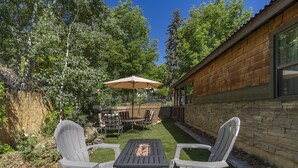 A patio with two Adirondack chairs, a table, and a large umbrella. - Renovated Home in Historic Downtown Durango (Durango)