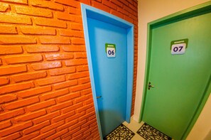 Un pasillo con dos puertas, una con la etiqueta '06' y la otra '07', y una pared de ladrillo.