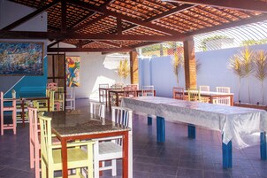 Un vaste espace intérieur doté de nombreuses tables et chaises, d’un grand tableau accroché au mur et d’un plafond orné de poutres en bois.