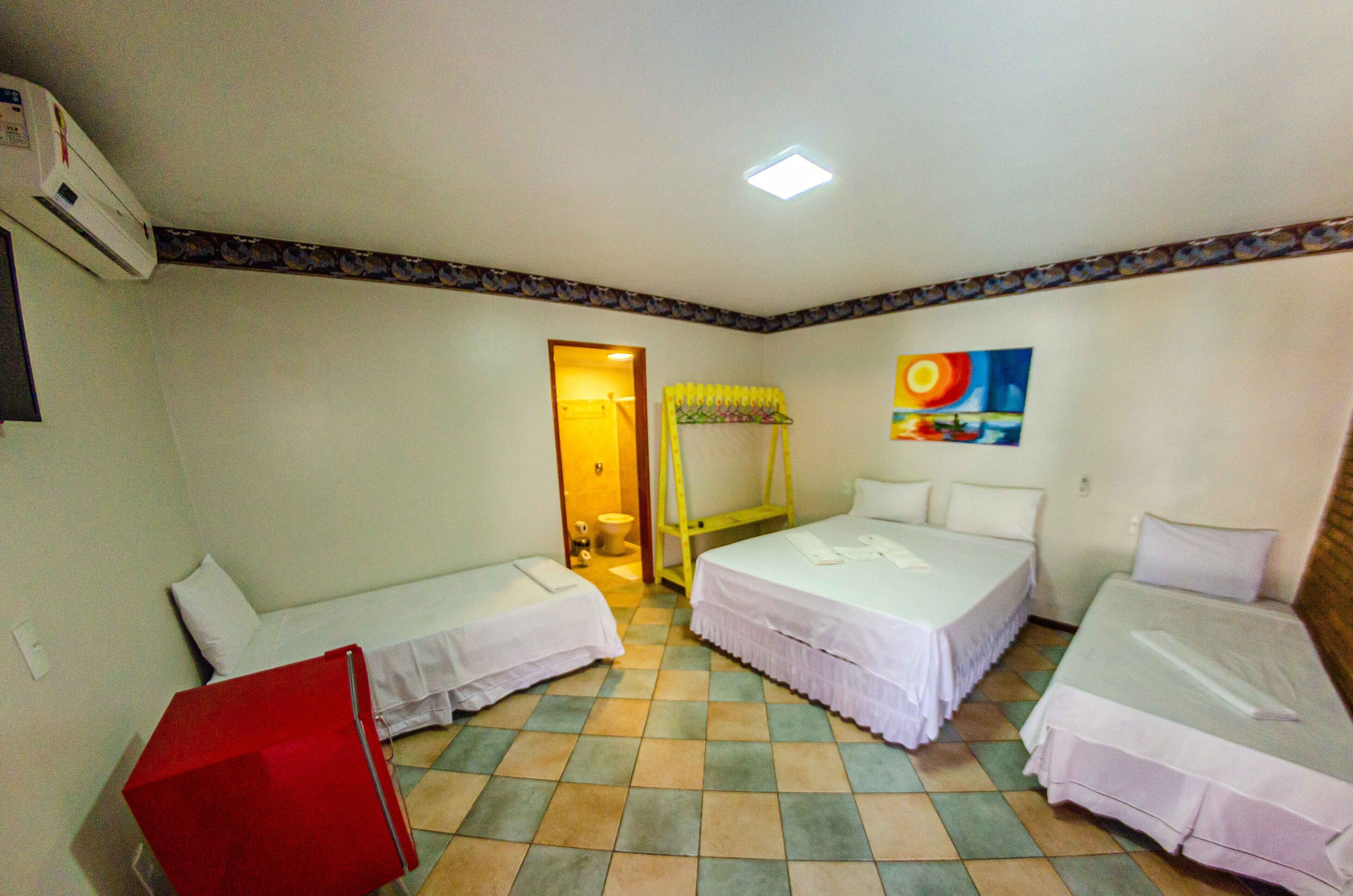 A room with two single beds, a red suitcase, a yellow bed frame, and a painting on the wall.