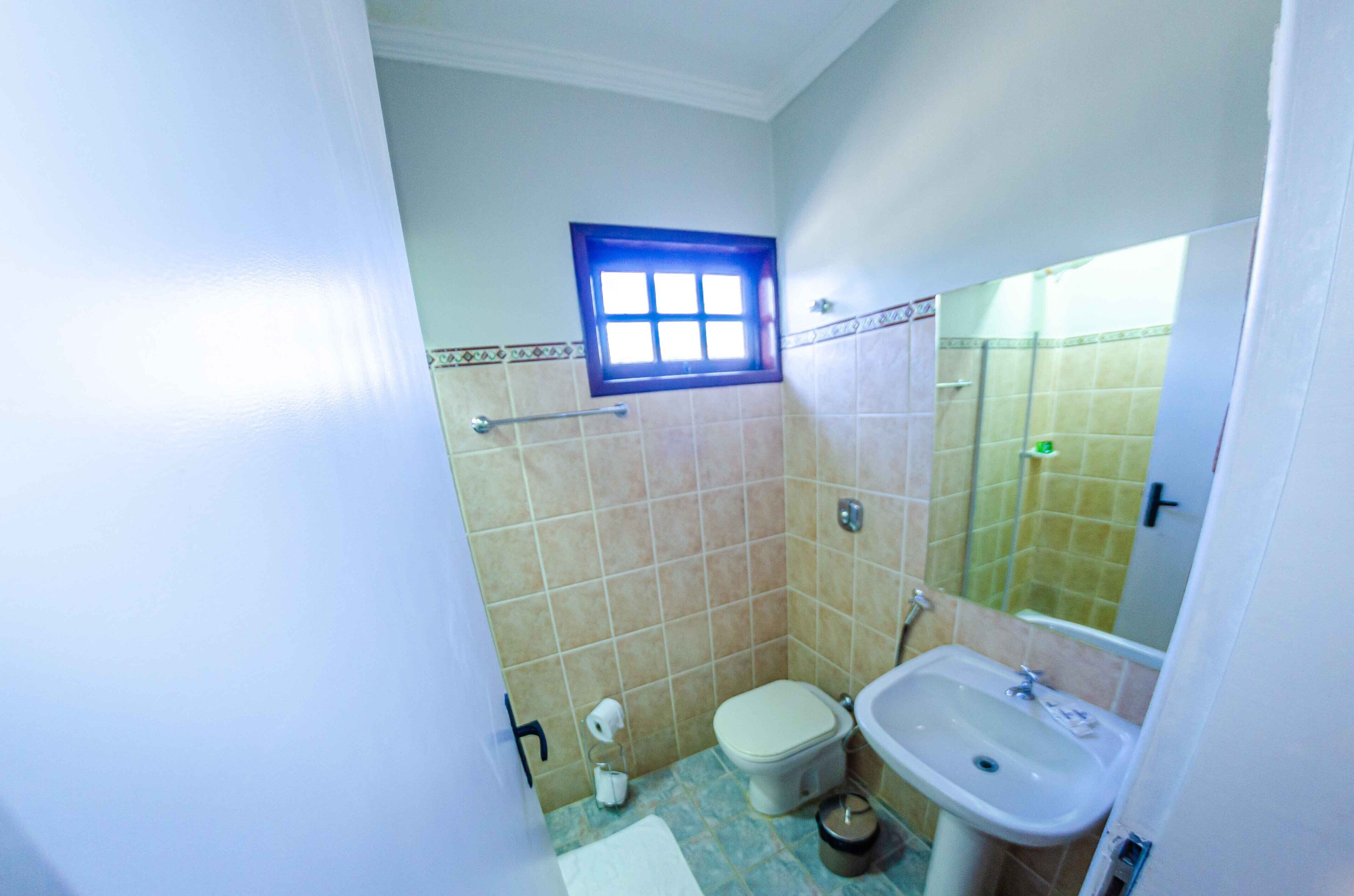 Ein kleines Badezimmer mit Toilette, Waschbecken und einem Fenster über der Toilette.