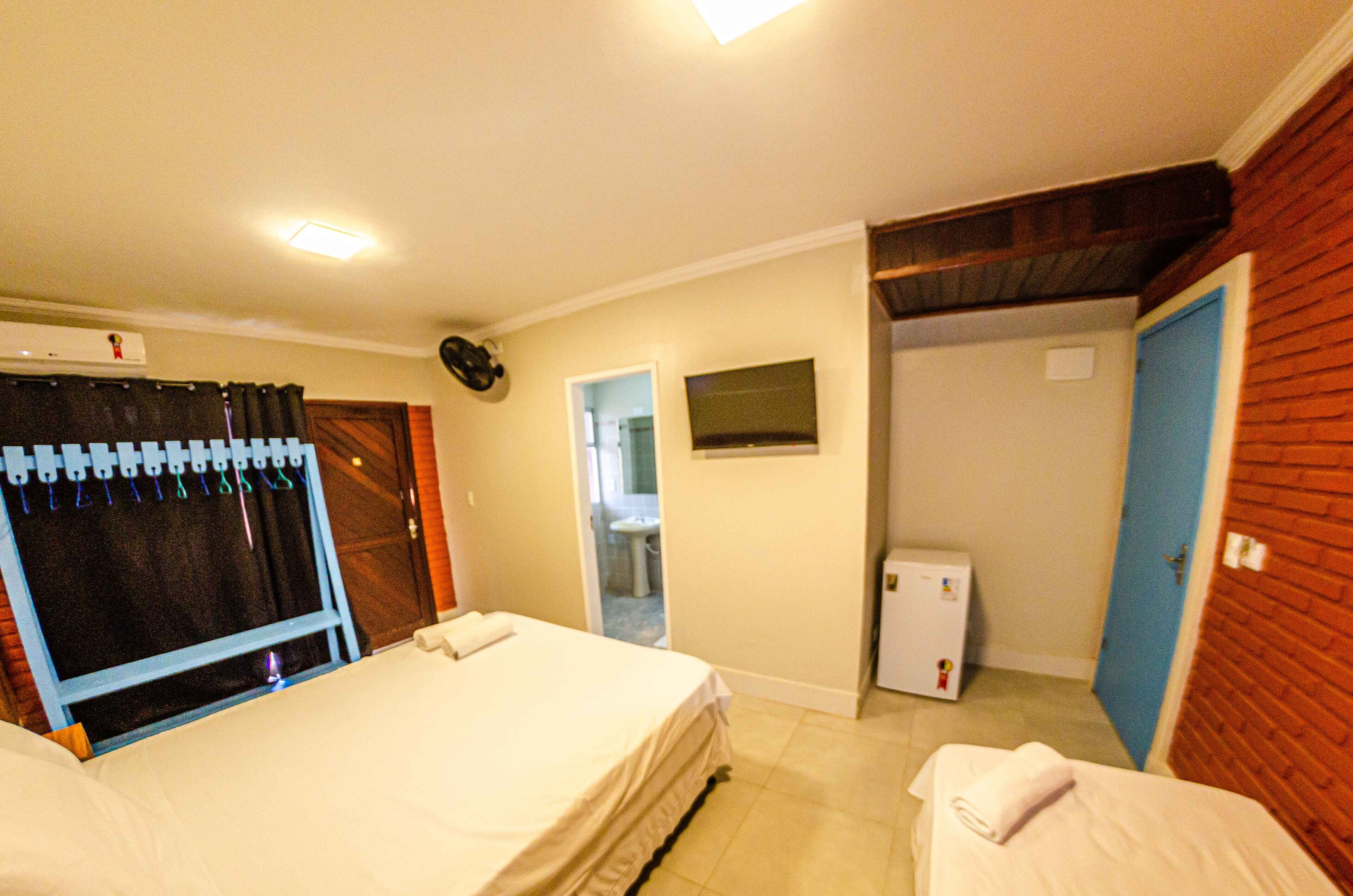 Een hotelkamer met een bed, een tafeltje, een wandheater, een deur en een raam.
