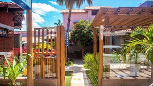 Un patio con una pérgola de madera, un camino empedrado y diferentes plantas.
