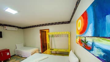 Una habitación con una cama, un banco, un armario rojo y un cuadro en la pared.