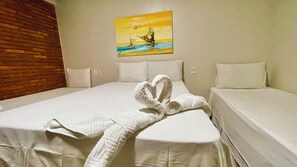 Habitación de hotel con una cama grande, un cuadro de un atardecer sobre el agua en la pared y una toalla doblada en forma de corazón sobre la cama.