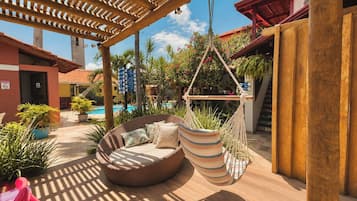 Un área junto a la piscina con una silla colgante, una hamaca y un pérgola de madera.
