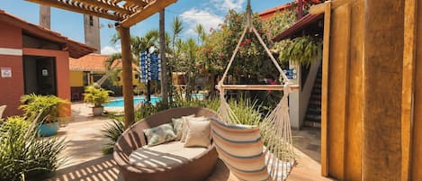 Ein Poolbereich mit einer Hängematte, einer Schaukelstuhlsitzgelegenheit und einer Holzpergola.