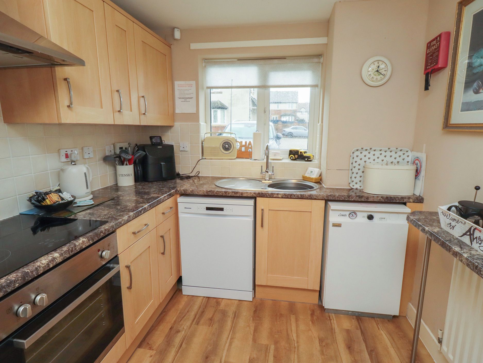 A compact kitchen with wooden cabinets, a black countertop, a dishwasher, and a stove.