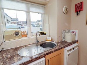 A kitchen with a sink, a vintage radio, a toy car, and a welcome pack on the counter. - Ahoy (Seahouses)