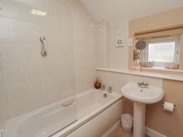 A bathroom with a bathtub, a sink, and a window with a mirror. - Ahoy (Seahouses)