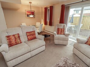 A living room with two sofas, a chair, a glass coffee table, and a dining table.