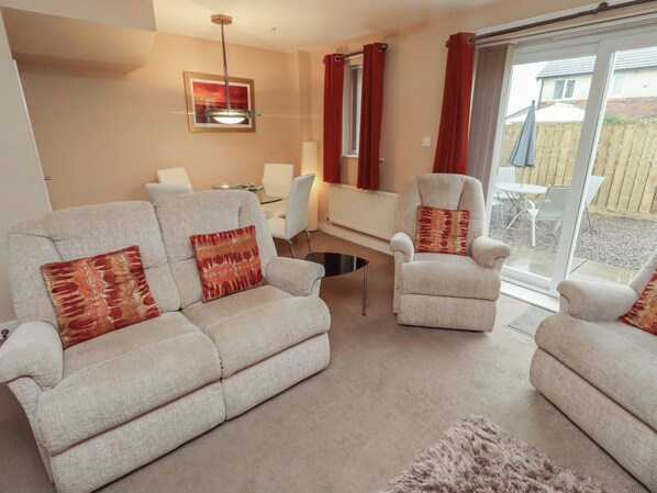 A living room with two sofas, a chair, a glass coffee table, and a dining table. - Ahoy (Seahouses)