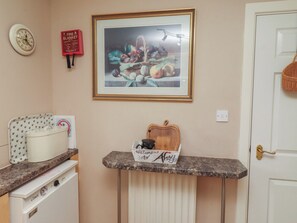 A kitchen area with a stove, a framed fruit still life, a fire blanket, and a welcome sign. - Ahoy (Seahouses)