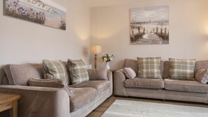 A living room with two sofas, a small table, and two wall-mounted lamps. - Southfield Lodge (Seahouses)