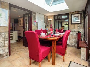 A dining area with a wooden table set for six, surrounded by red upholstered chairs.