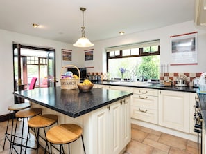 A kitchen with a large island, bar stools, a sink, and a window with a view of greenery.