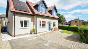A two-story house with a red-tiled roof, a front porch, and a gravel driveway. - The Chevy (Seahouses)