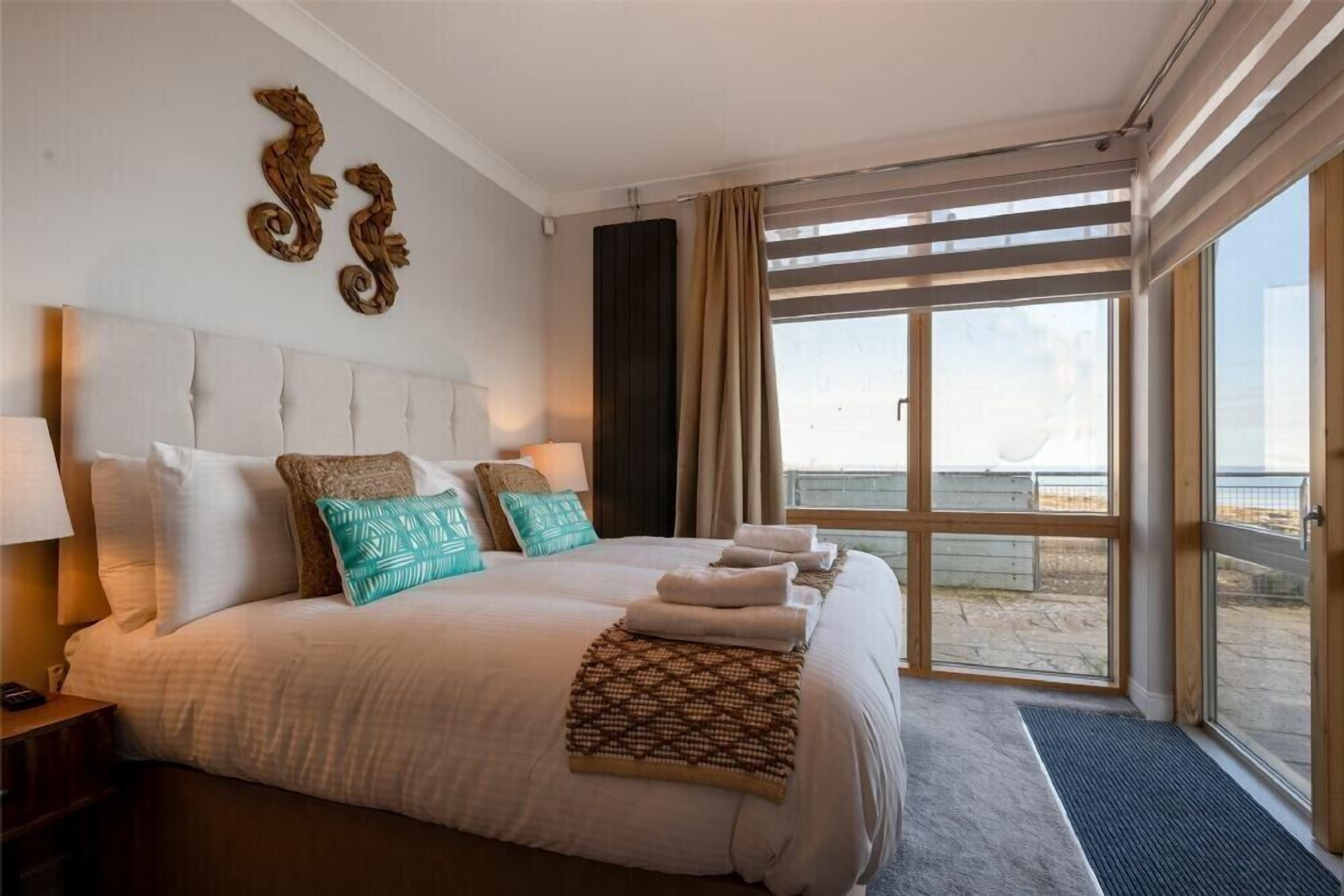 A hotel room with a large bed, a view of the beach, and a balcony.
