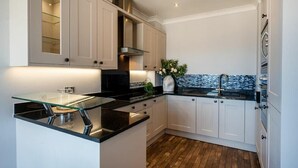 Una cucina moderna con pensili bianchi, un piano di lavoro nero e un'isola in vetro.