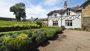 A traditional building with a gabled roof and a chimney, surrounded by well-maintained gardens and a gravel driveway. - Garden House (Alnwick)