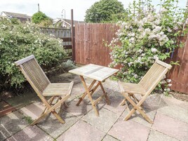 Une terrasse avec deux chaises en bois et une table carrée.