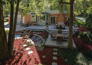 Enjoy the serene atmosphere on the spacious deck with a table and chairs, surrounded by mature trees and beautifully landscaped gardens.