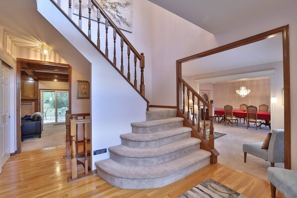 Stunning interior space with a grand staircase, dining area, and chandelier.