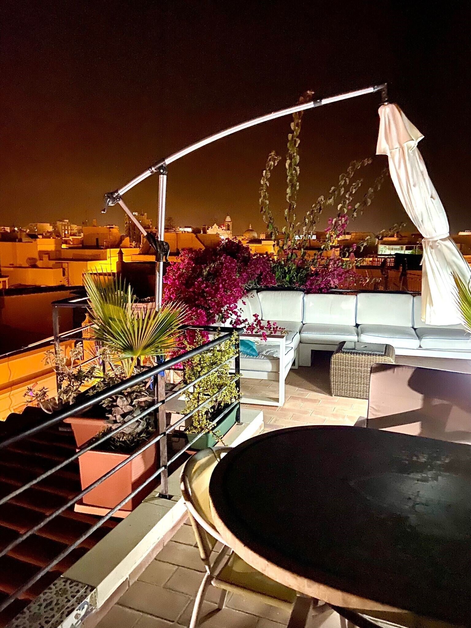 Una terrazza sul tetto con un tavolo rotondo, un divano e piante in vaso.