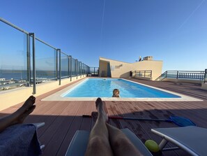 Una piscina al aire libre, sombrillas, sillones reclinables de piscina